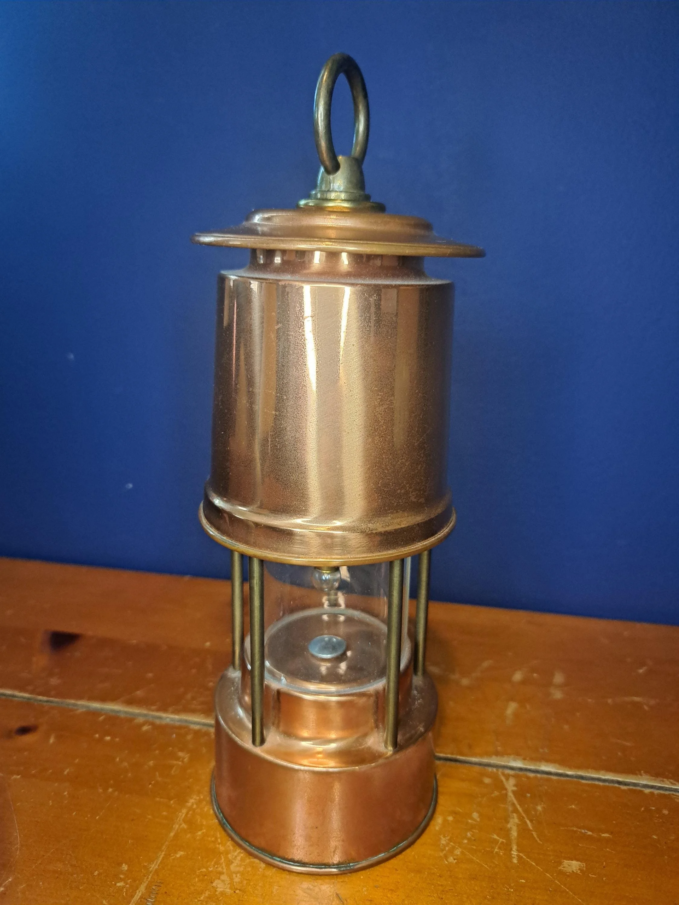 Solid copper miner's lantern photographed against a blue backdrop.